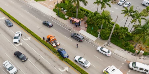 Aerial view of a car accident on a street lined with palm trees