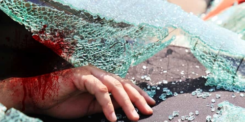 A shattered windshield with a bloody hand on the dashboard