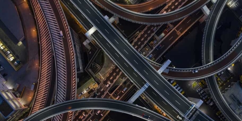 Aerial view at night of several freeway overpasses that all intersect at once