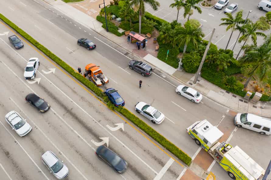 Aerial view of a car accident on a street lined with palm trees