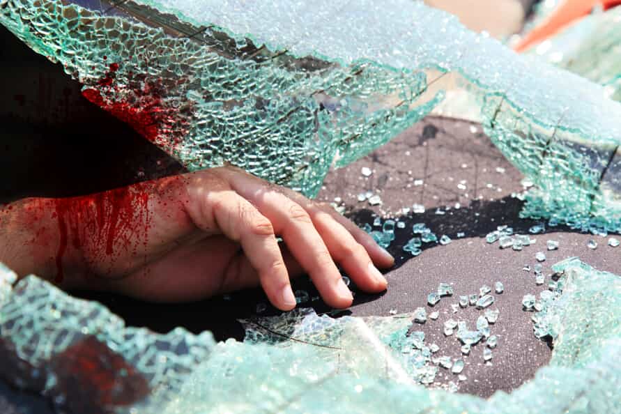 A shattered windshield with a bloody hand on the dashboard