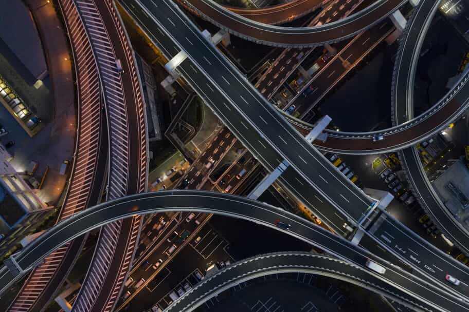 Aerial view at night of several freeway overpasses that all intersect at once