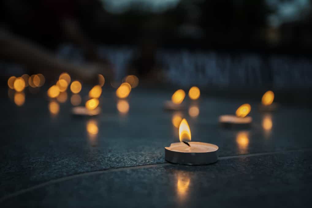 Lit tealights sit on a dark headstone
